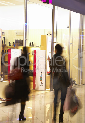 Two girls in shopping center near a show-window of shop