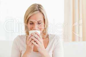 Smiling woman smelling her cup of coffee