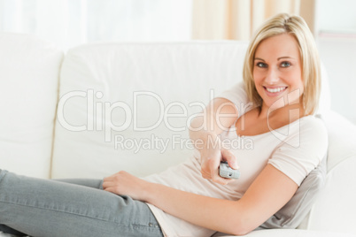 Woman pointing a remote at the camera with a knowing smile