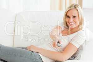 Woman pointing a remote at the camera with a knowing smile
