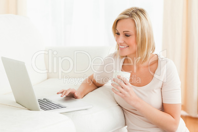 Woman holding a mug while using a notebook