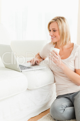 Portrait of awoman holding a mug while using a notebook