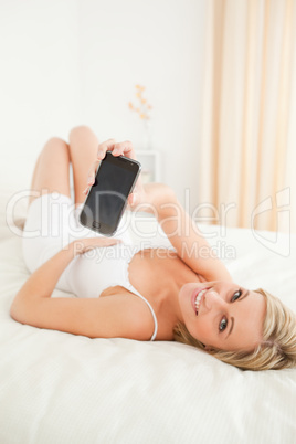 Portrait of a charming woman showing her smartphone