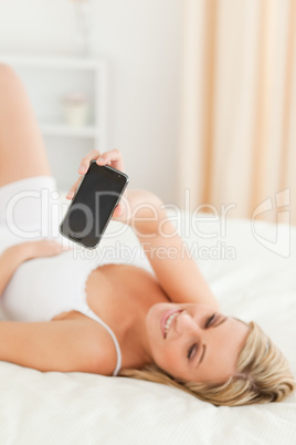 Portrait of a cute blonde woman showing her phone