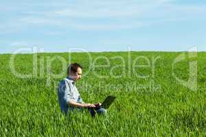 young man using laptop in the field