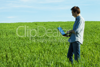 young man using laptop in the field