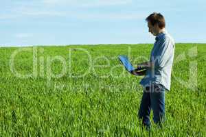 young man using laptop in the field