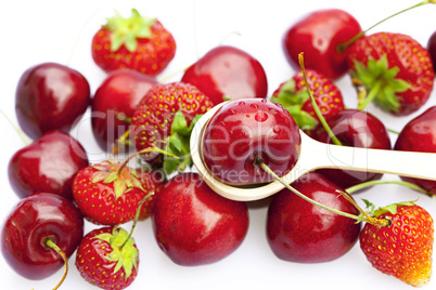 cherry and strawberry in a spoon isolated on white