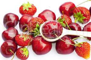 cherry and strawberry in a spoon isolated on white