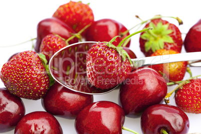 cherry and strawberry in a spoon isolated on white