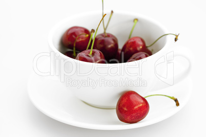 cup saucer and cherries isolated on white