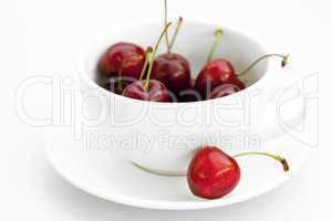 cup saucer and cherries isolated on white