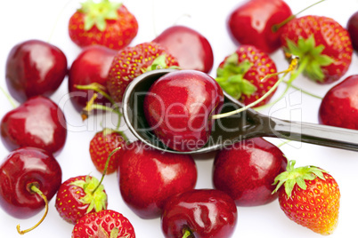 cherry and strawberry in a spoon isolated on white