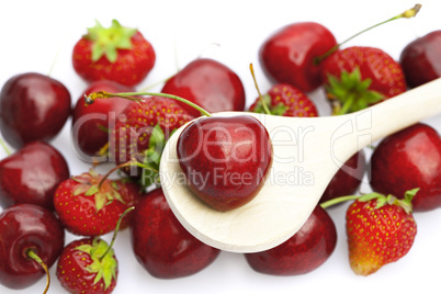 cherry and strawberry in a spoon isolated on white