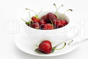 cup saucer spoon cherries and strawberries isolated on white