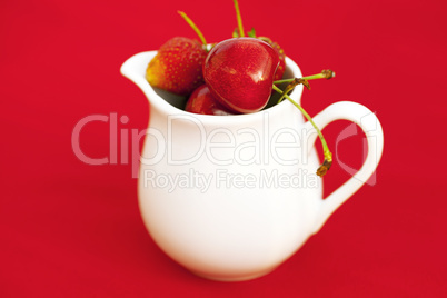 milk jug  cherry and strawberry on a red background