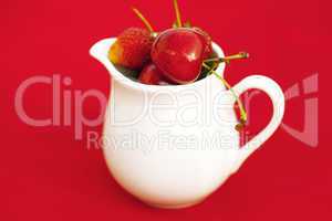 milk jug  cherry and strawberry on a red background