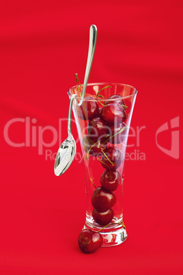 glass of cherry and spoon on a red background