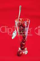 glass of cherry and spoon on a red background