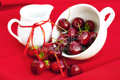 milk jug with a ribbon  cherries and strawberries in a white cup