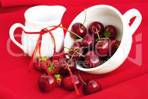 milk jug with a ribbon  cherries and strawberries in a white cup
