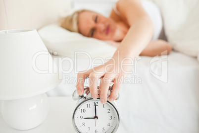Upset woman switching off her alarm clock