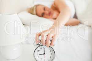 Upset woman switching off her alarm clock