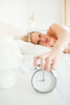 Portrait of a tired woman switching off her alarm clock