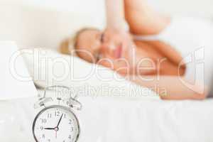 Tired woman awaked by her alarm clock