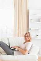 Portrait of a woman with a laptop while lying on a sofa