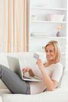 Portrait of a woman buying online whilie lying on a couch