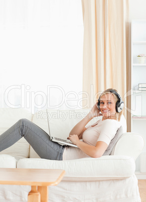 Portrait of a smling woman with a laptop and headphones