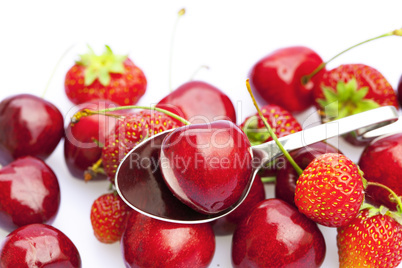 cherry and strawberry in a spoon isolated on white