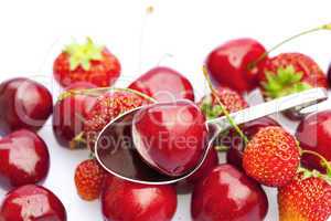 cherry and strawberry in a spoon isolated on white