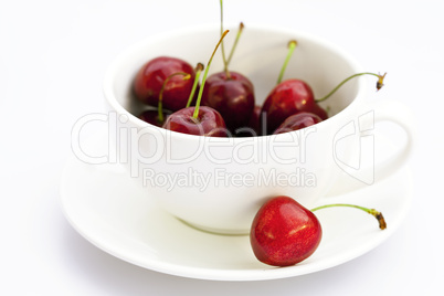 cup saucer and cherries isolated on white