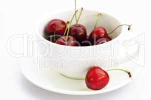 cup saucer and cherries isolated on white
