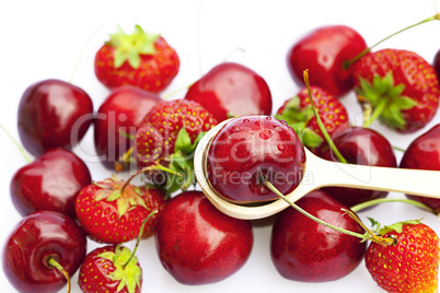 cherry and strawberry in a wooden spoon isolated on white