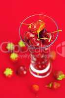 glass of cherry and strawberry on a red background