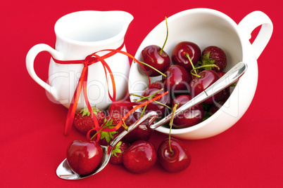 milk jug with a ribbon  cherries and strawberries in a white cup