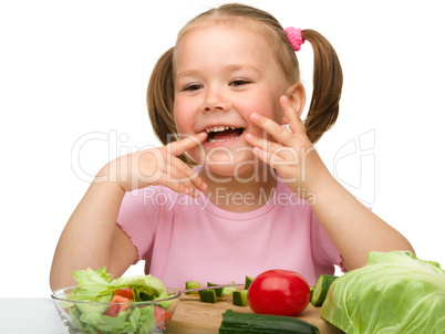 Little girl is cutting carrot for salad