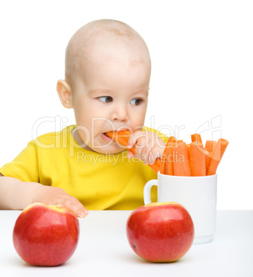 Cute little boy eats carrot and apples