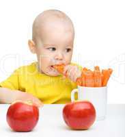 Cute little boy eats carrot and apples