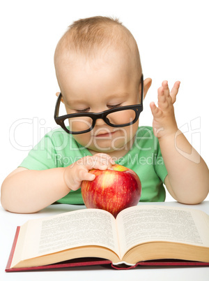 Little child is playing with red apple