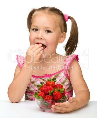 Happy little girl eats strawberries