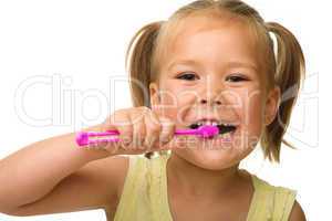 Little girl is cleaning teeth using toothbrush