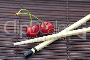 cherry and chopsticks on bamboo mat