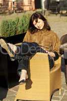 beautiful young woman sitting on a wicker chair