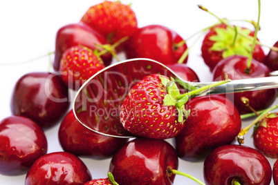 cherry and strawberry in a spoon isolated on white