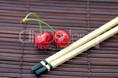 cherry and chopsticks on bamboo mat