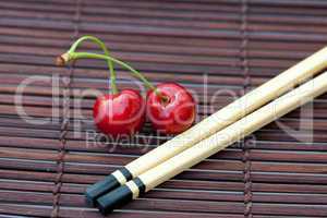 cherry and chopsticks on bamboo mat